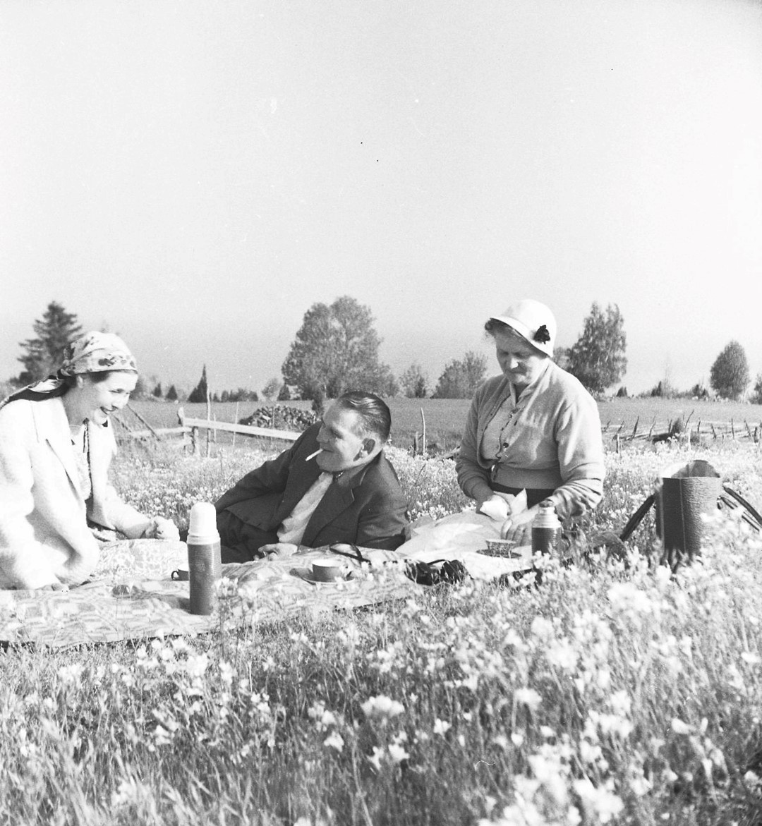 Gökotta. En man och två kvinnor har picknick på en äng. 